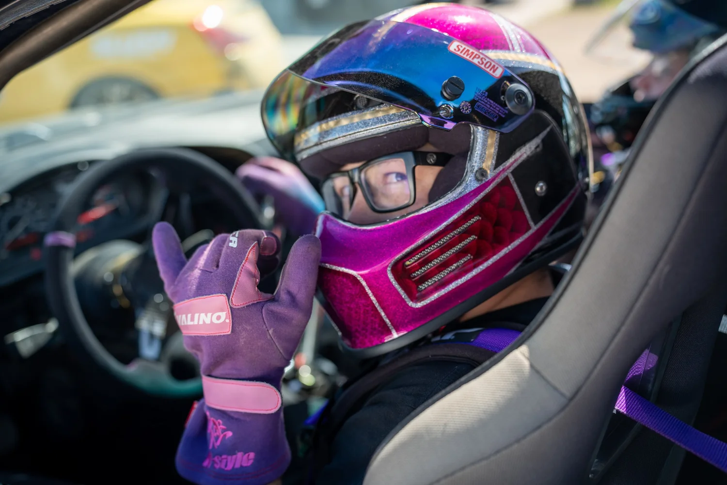 Wyatt Fogleman in a pink and purple helmet, throwing horns from the driver's seat