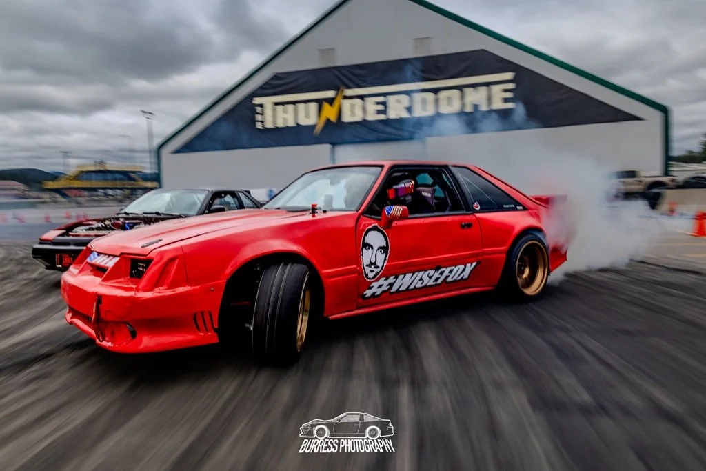 Red Fox body Mustang drifting in front of the Thunderdome building